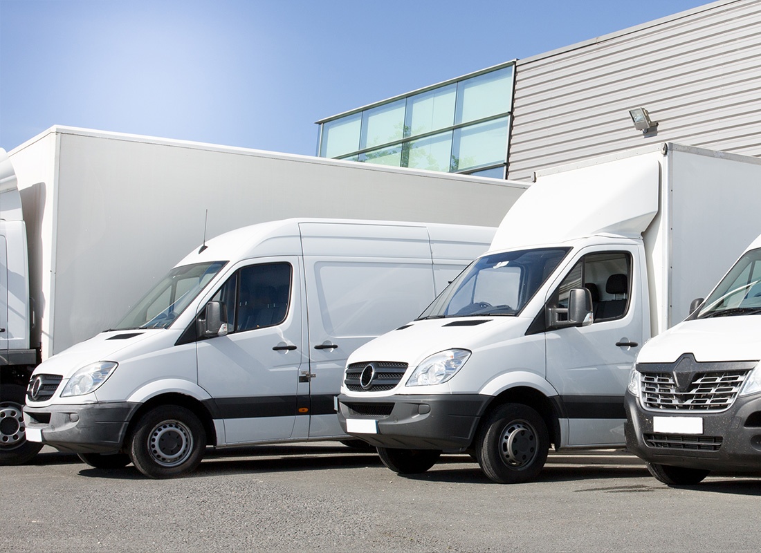 Business Insurance - White Company Vans Parked in a Company Parking Lot on a Clear Sunny Day