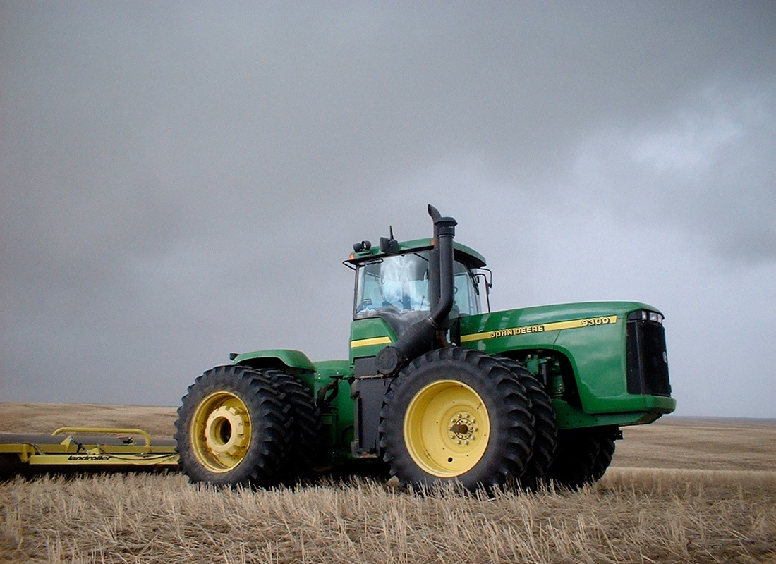 Insurance Solutions - A Shot of a Green Tractor in the Middle of Farmlands With Grey Clouds in the Background